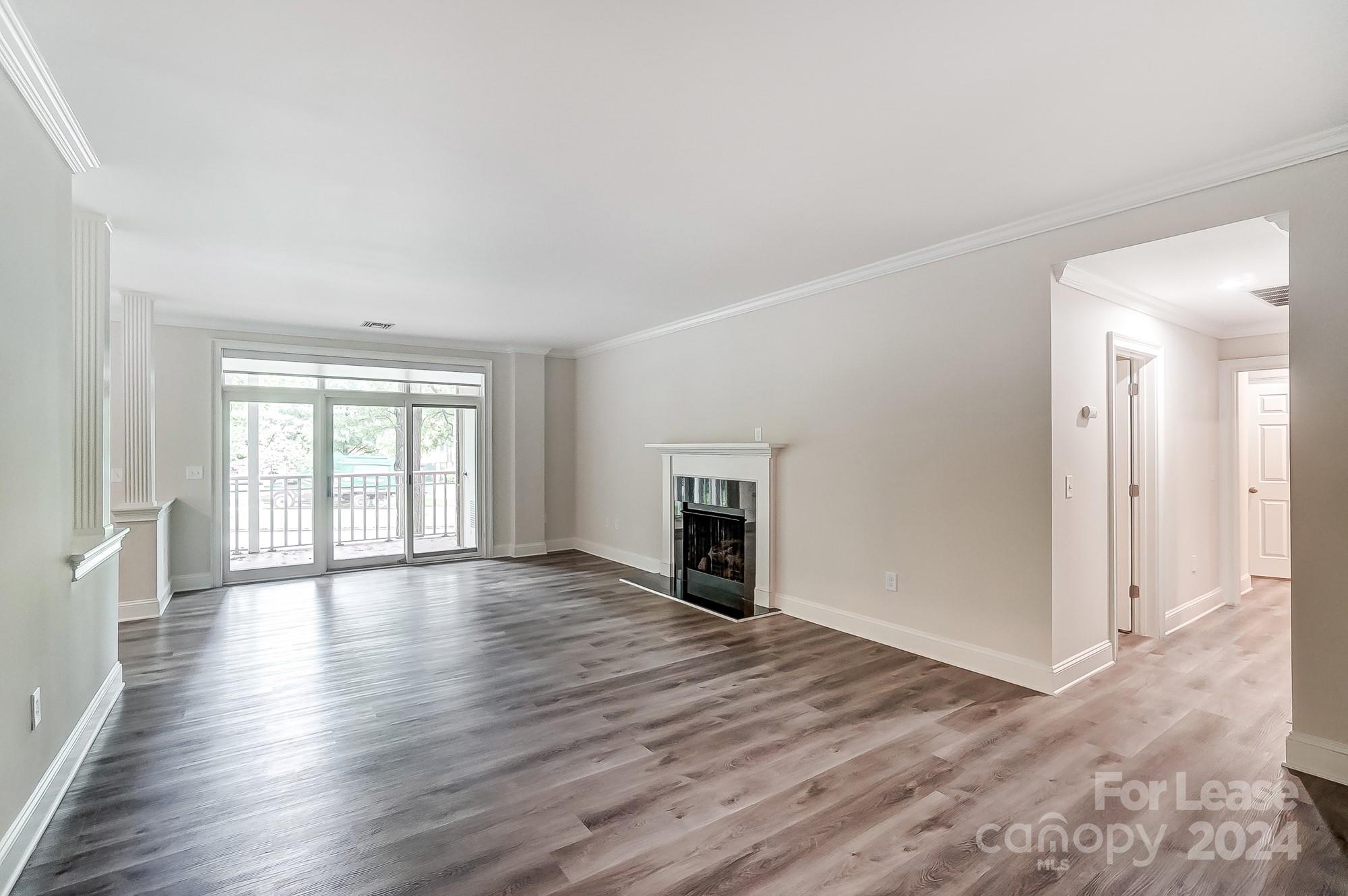 1301 Queens Road, Unit 205 Charlotte, NC 28207 - Photo 8 of 23 a view of an empty room with wooden floor and a window