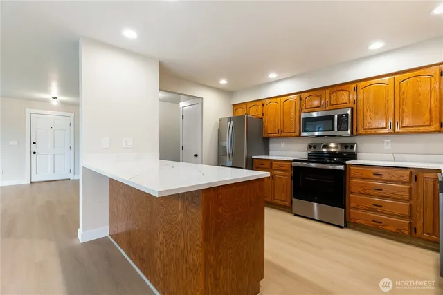 a kitchen with stainless steel appliances granite countertop a stove a sink and a refrigerator with wooden floor