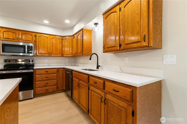 a kitchen with stainless steel appliances granite countertop a sink a stove and cabinets