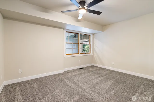 an empty room with windows and fan