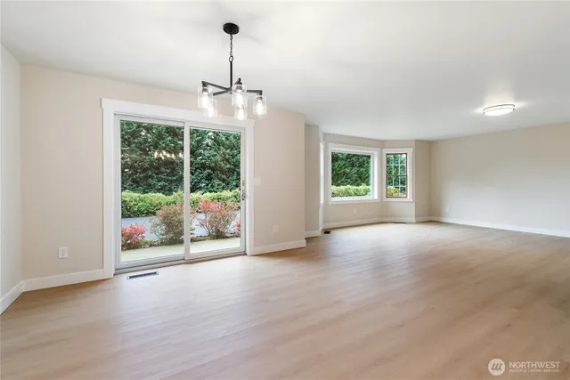 an empty room with wooden floor outdoor space and windows