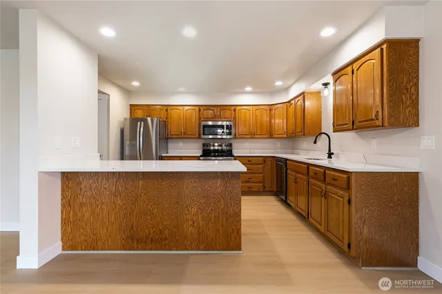 a kitchen with stainless steel appliances granite countertop a sink a stove and a refrigerator