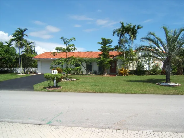 a front view of a house with a yard and palm trees