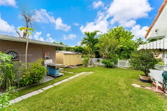 a backyard of a house with table and chairs plants and large tree