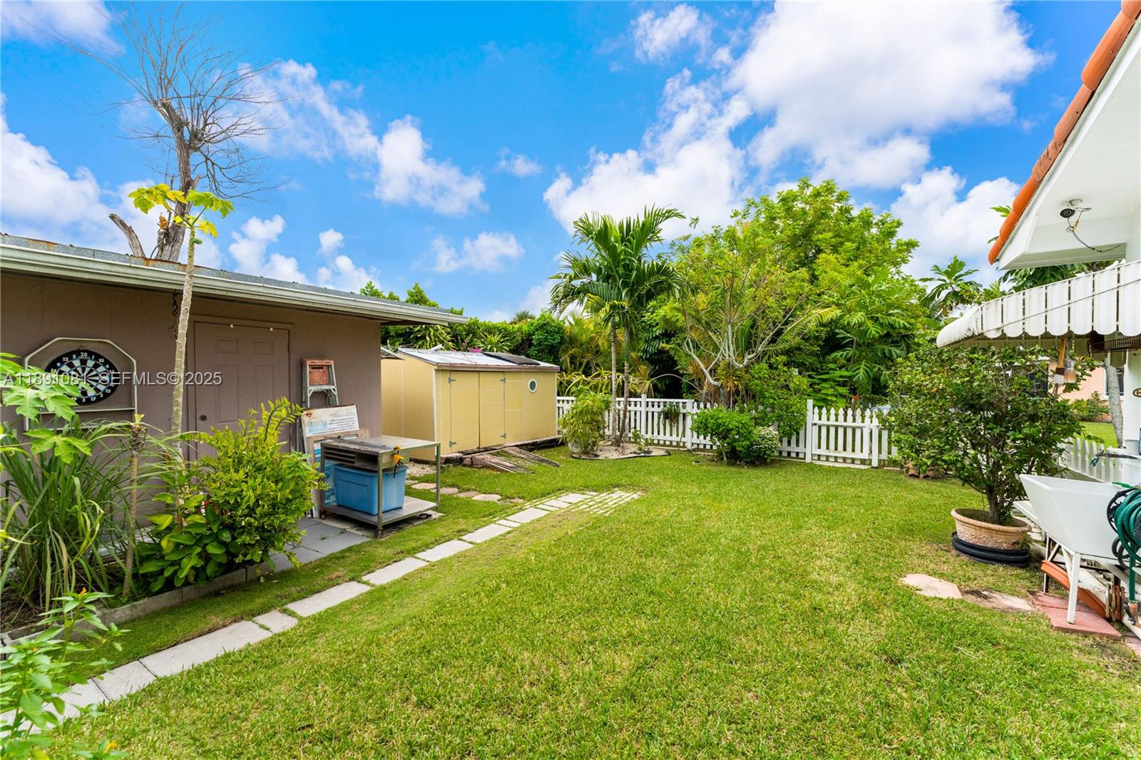 9081 Southwest 140th Street Miami, FL 33176 - Photo 4 of 29 a backyard of a house with table and chairs plants and large tree