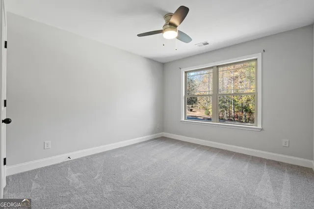 a view of a white house with a yard plants and large tree