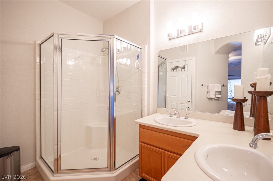 7701 West Robindale Road, Unit 274 Las Vegas, NV 89113 - Photo 31 of 38 This bathroom features a double vanity and a glass-enclosed shower, offering comfort and style.