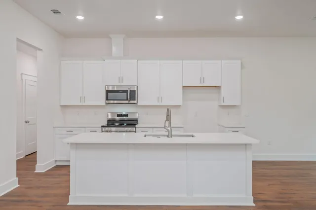 a kitchen with stainless steel appliances granite countertop a stove a sink and white cabinets