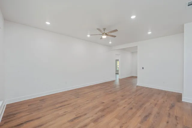 an empty room with wooden floor and ceiling fan