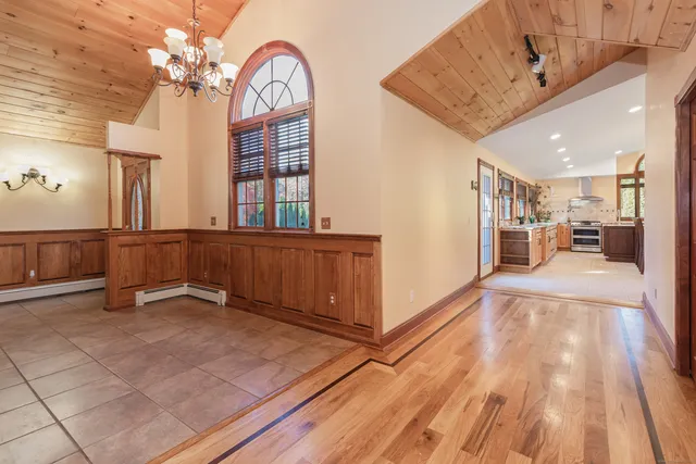 a view of a living room a kitchen with furniture wooden floor and a chandelier