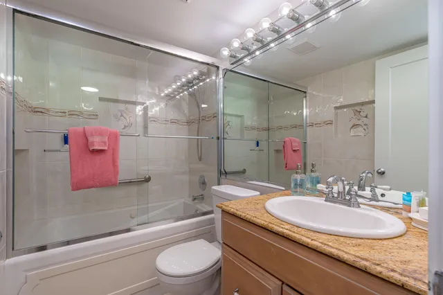 a bathroom with a granite countertop sink a toilet a mirror and shower