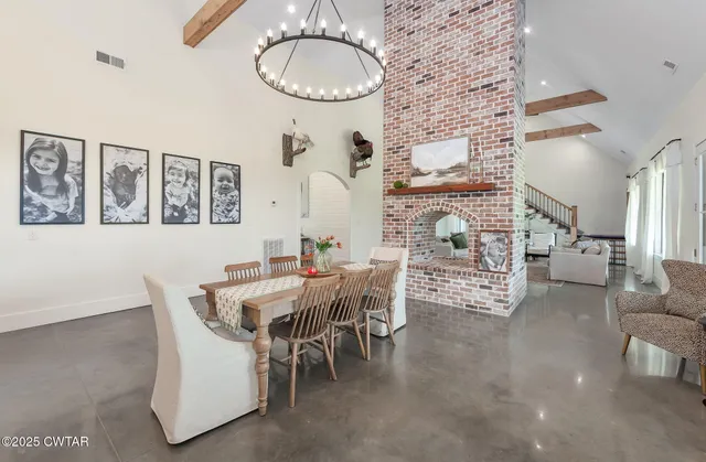 a view of dining room and livingroom with furniture wooden floor a rug a painting and a chandelier