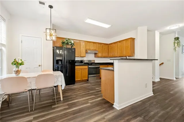 a kitchen with stainless steel appliances granite countertop a refrigerator a stove top oven a sink dishwasher and white cabinets with wooden floor