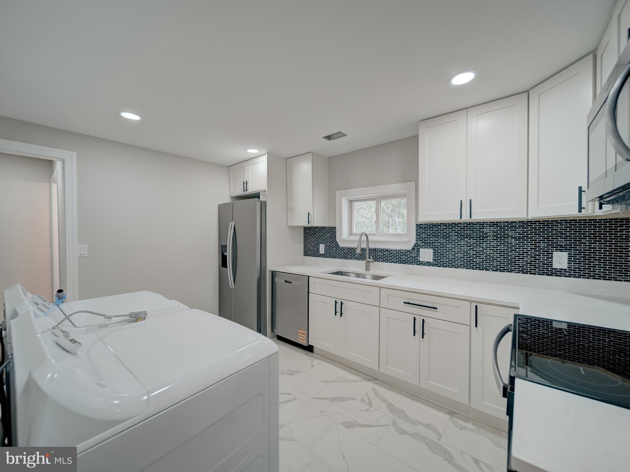 401 Bryan Point Road Accokeek, MD 20607 - Photo 24 of 48 a kitchen with white cabinets and stainless steel appliances