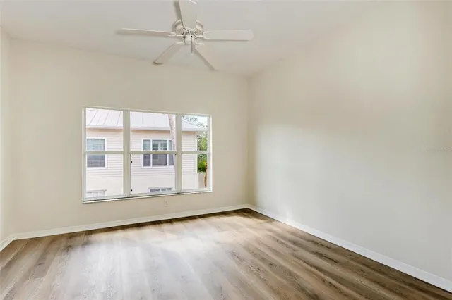 an empty room with wooden floor fan and windows
