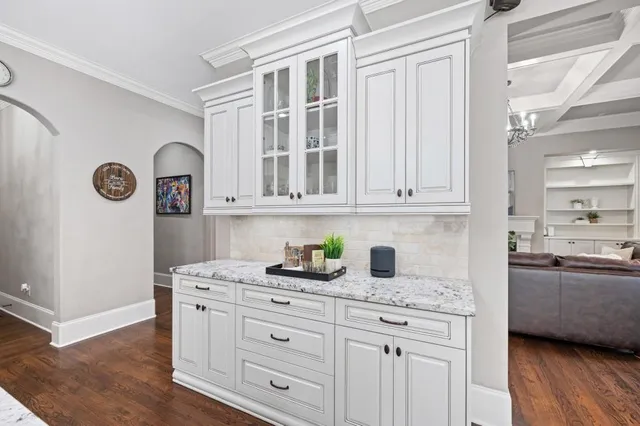 a kitchen with stainless steel appliances a stove a chandelier a dining table and chairs with wooden floor