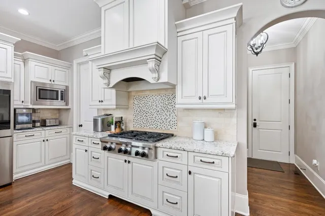 a kitchen with stainless steel appliances kitchen island granite countertop a table chairs and a refrigerator