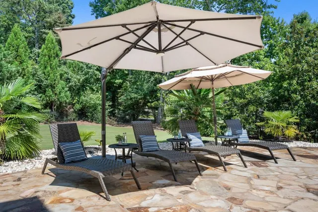 a view of a patio with table and chairs potted plants and a floor to ceiling window