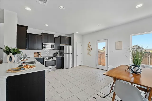 a kitchen with stainless steel appliances kitchen island granite countertop a refrigerator a stove a sink dishwasher and a dining table with wooden floor