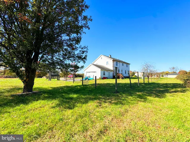 a white house with a big yard and large trees