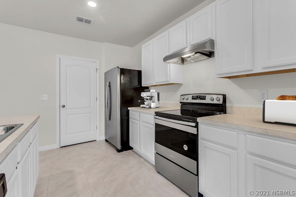101 Old Mill Pond Road Palm Harbor, FL 34683 - Photo 5 of 20 a kitchen with stainless steel appliances a refrigerator a stove and white cabinets