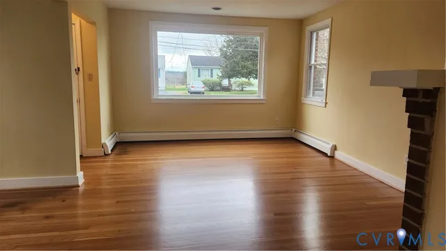 a view of an empty room with wooden floor and a window