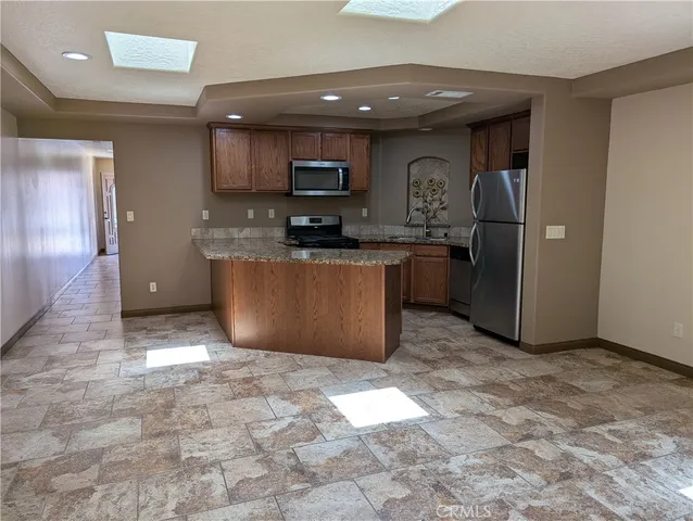 a kitchen with stainless steel appliances granite countertop a refrigerator a stove top oven and a sink