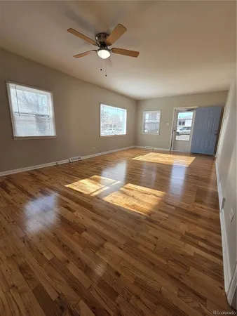 a view of an empty room with window and wooden floor