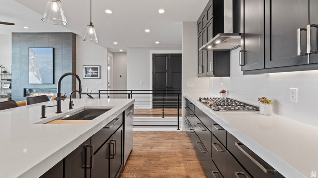 355 East Overlook Loop Hideout, UT 84036 - Photo 13 of 40 Contemporary kitchen featuring an oversized island with an integrated sink, dark wood-finish cabinetry, a gas cooktop, and light-toned countertops with a matching backsplash