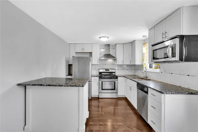 a kitchen with stainless steel appliances granite countertop a sink stove microwave and refrigerator