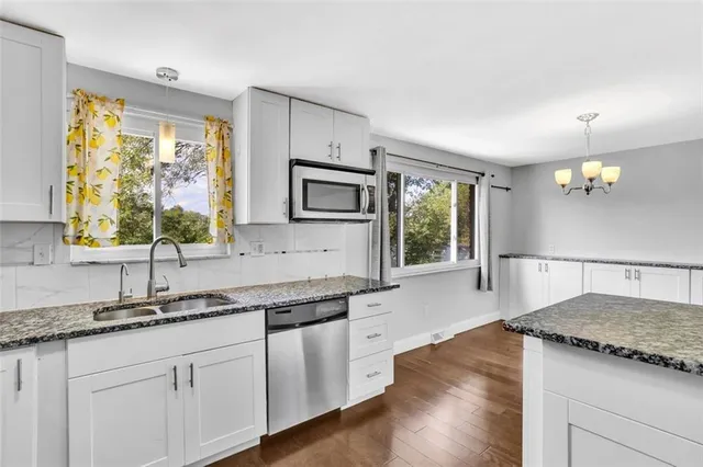 a kitchen with stainless steel appliances granite countertop a sink a stove cabinets and wooden floor