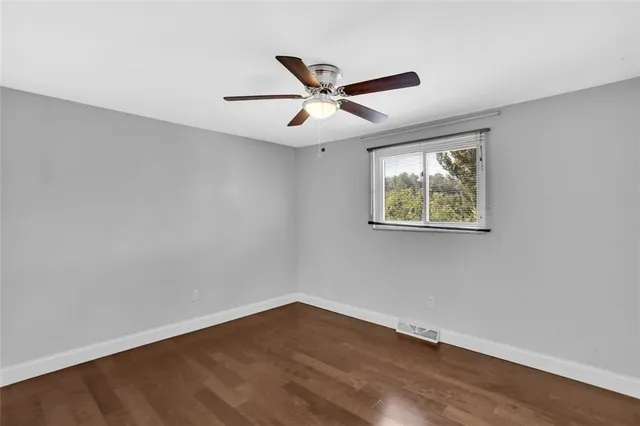 an empty room with wooden floor and ceiling fan