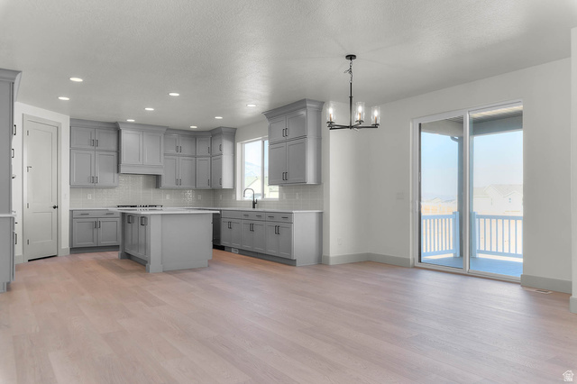 562 West Coyote Rdg Road Grantsville, UT 84029 - Photo 12 of 27 Spacious open-concept kitchen with light wood-finish flooring, grey cabinetry, a central island, and a tile backsplash