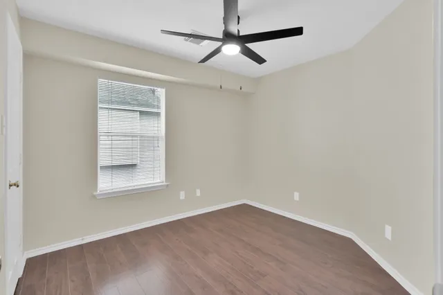 an empty room with a window and a ceiling fan