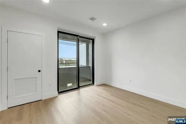 a view of an empty room with wooden floor and closet