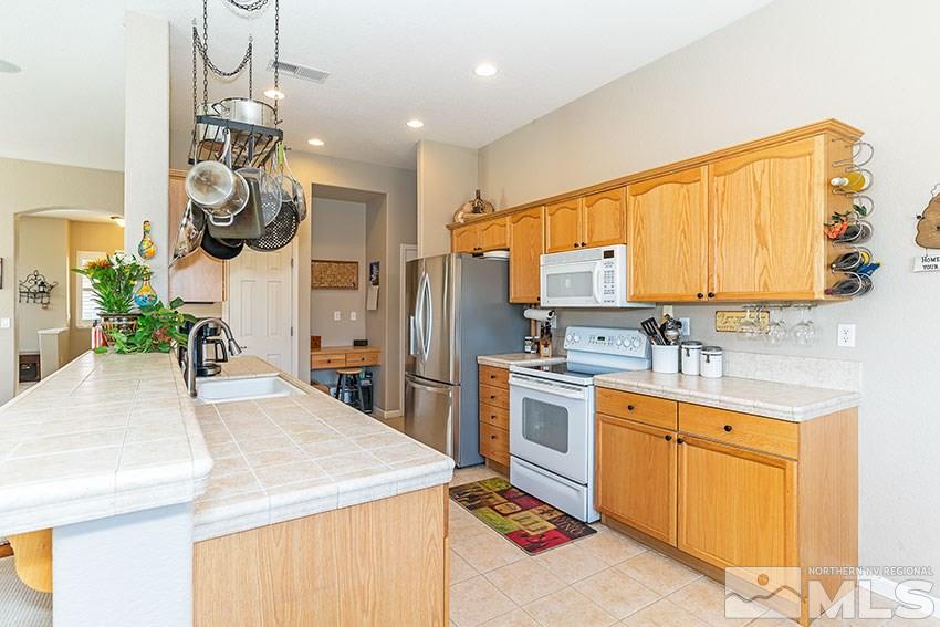 10220 Donnay Court Reno, NV 89521 - Photo 7 of 19 a kitchen with stainless steel appliances kitchen island granite countertop a sink dishwasher a refrigerator and cabinets with wooden floor