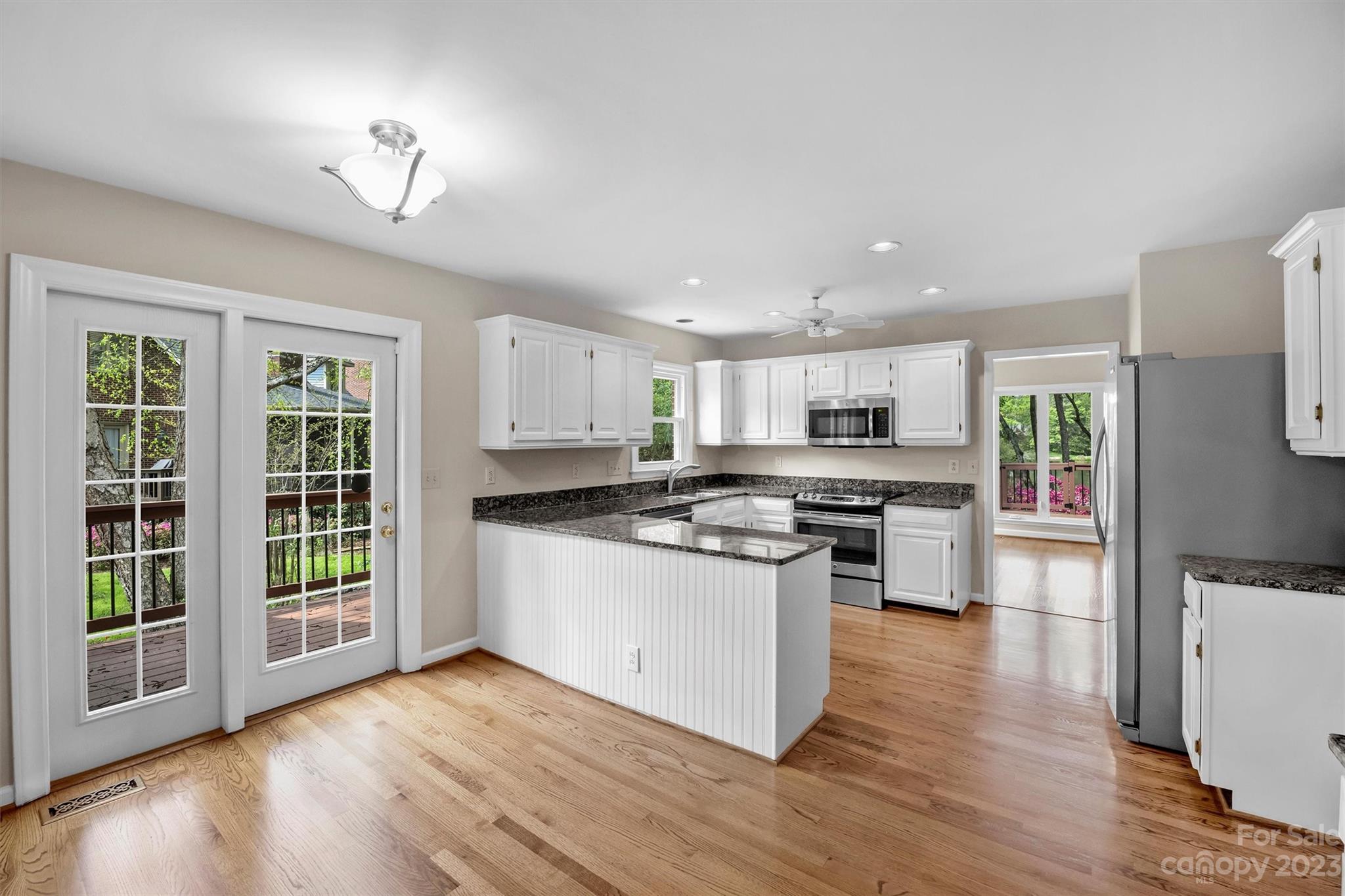 4724 Carson's Pond Road, Unit 104 Charlotte, NC 28226 - Photo 13 of 38 a kitchen with stainless steel appliances kitchen island wooden floors and white cabinets