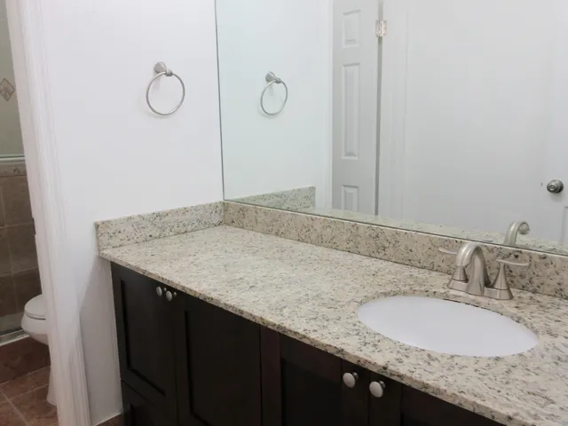 a bathroom with a granite countertop sink and a mirror