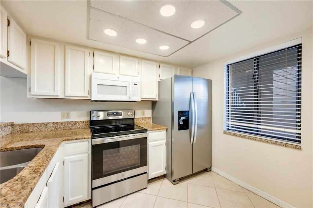 5825 Rattlesnake Hammock Road, Unit 107 Naples, FL 34113 - Photo 14 of 38 a kitchen with granite countertop white cabinets and stainless steel appliances
