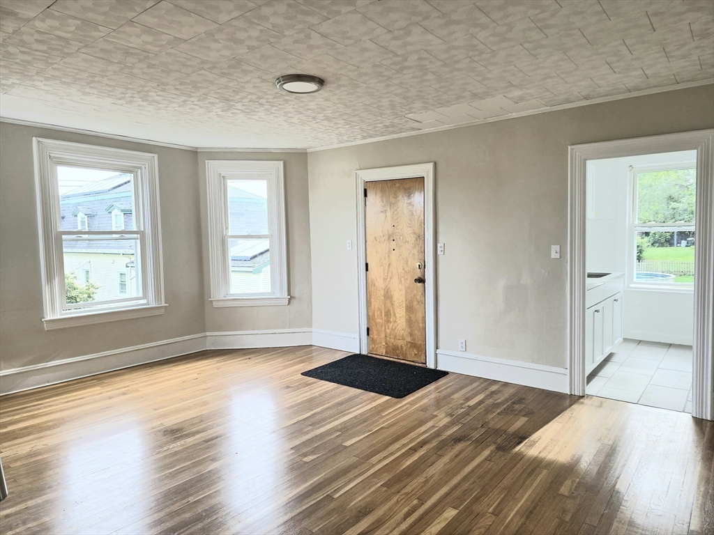 24 Ash Street, Unit 3 Fall River, MA 02724 - Photo 4 of 15 an empty room with wooden floor and windows