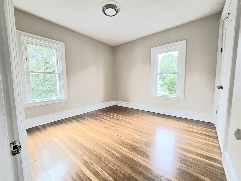 24 Ash Street, Unit 3 Fall River, MA 02724 - Photo 9 of 15 an empty room with wooden floor and windows