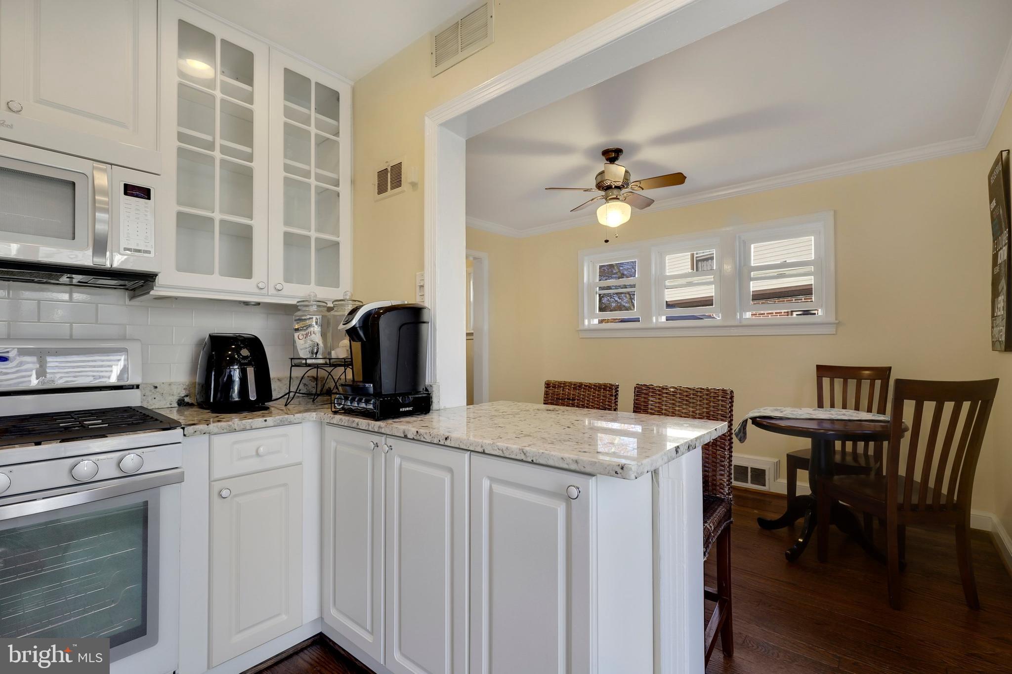 9515 Riley Road Silver Spring, MD 20910 - Photo 15 of 43 a kitchen with stainless steel appliances granite countertop a stove a sink dishwasher and white cabinets with wooden floor