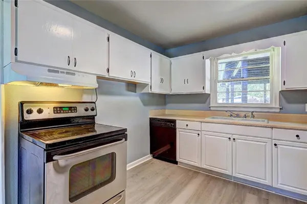 a kitchen with cabinets appliances and wooden floor