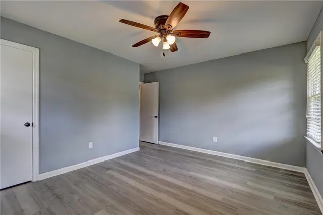 a view of an empty room with window and wooden floor