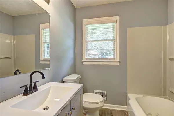 a bathroom with a toilet a sink a mirror a window and vanity