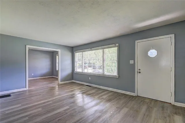 an empty room with wooden floor and windows