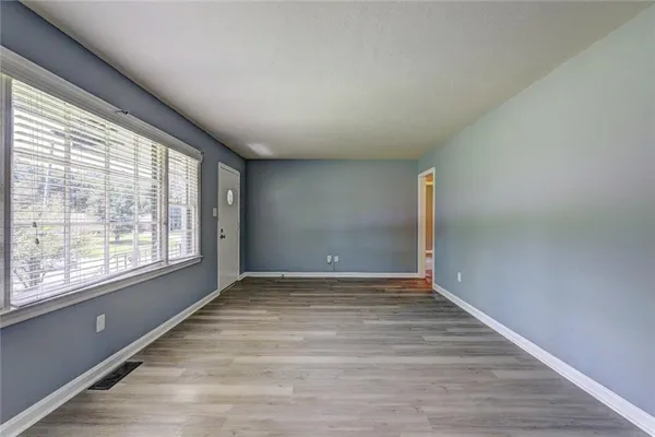 a view of an empty room with wooden floor and a window