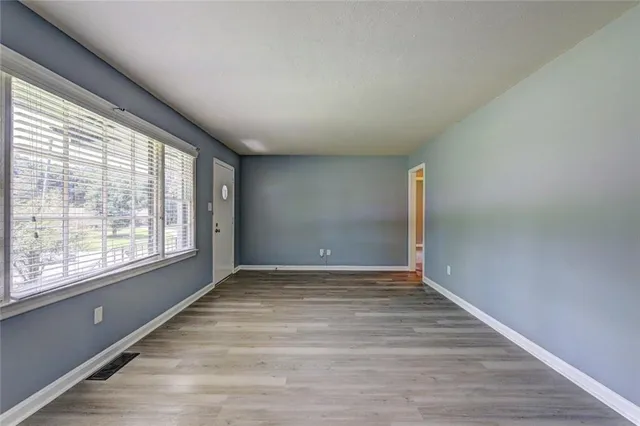 a view of an empty room with wooden floor and a window