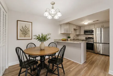 a kitchen with stainless steel appliances granite countertop a dining table and chairs