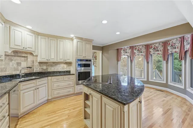 a kitchen with stainless steel appliances granite countertop a sink a stove and white cabinets